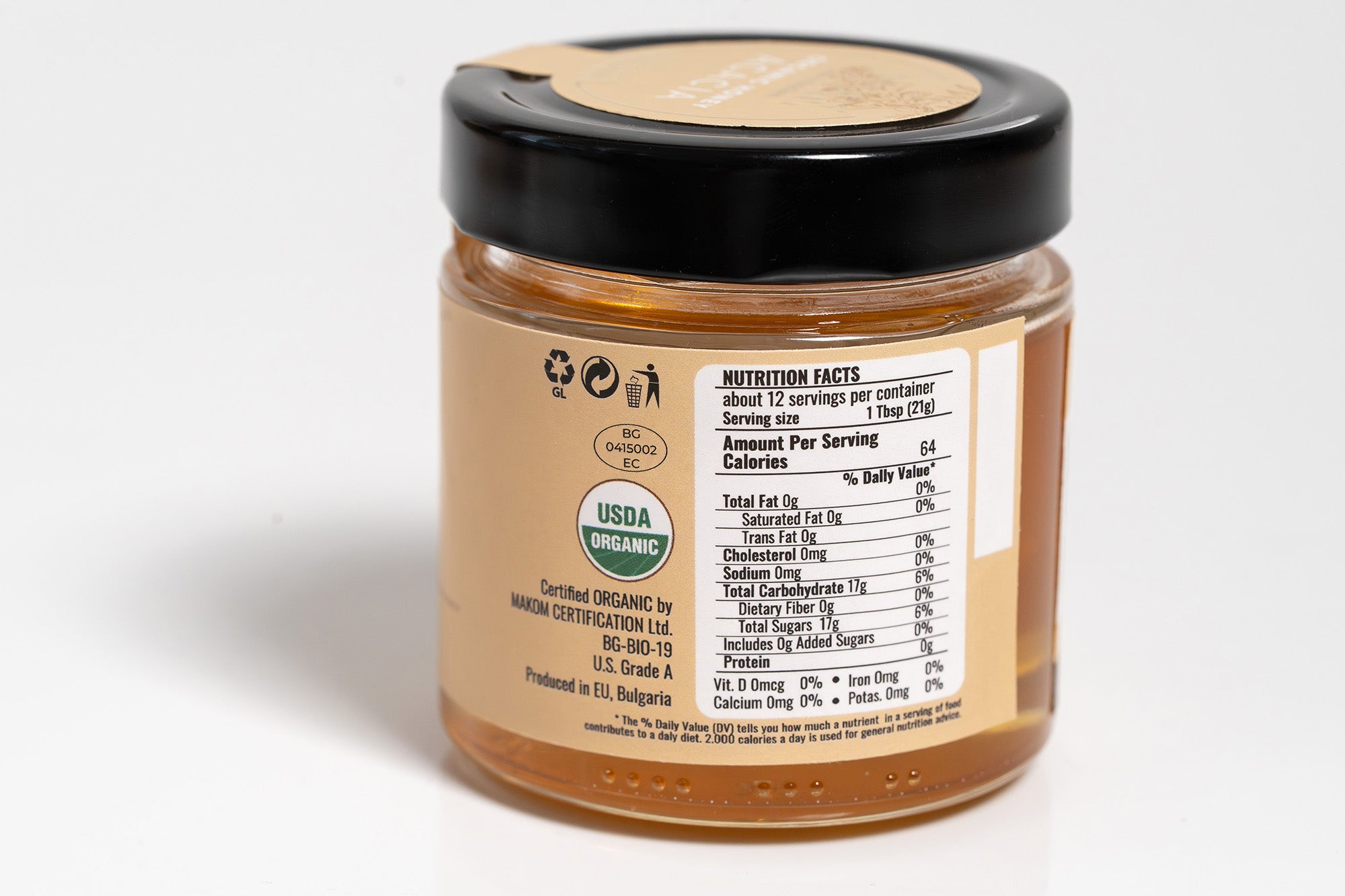 Clear jar of creamy peanut butter showing the back side with a detailed nutrition facts label and ingredient list. The jar is placed on a clean white background, highlighting the product’s nutritional information and packaging.