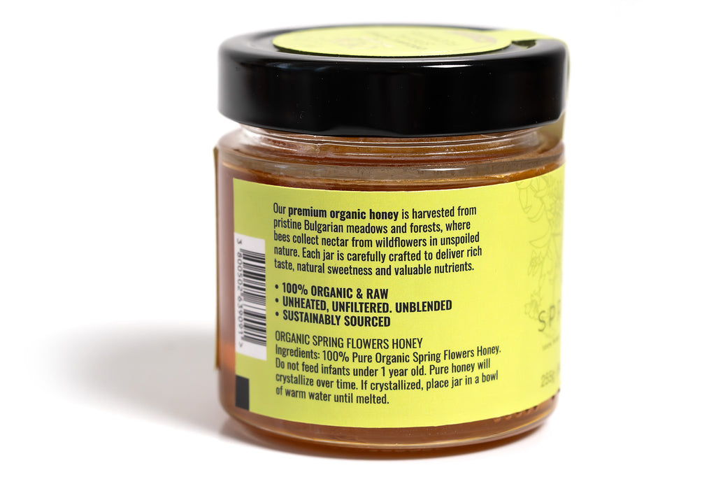 Clear glass jar filled with golden honey, featuring a bright yellow label with clean, modern design. The jar is displayed against a white background, emphasizing the rich amber color of the honey and the vibrant label, ideal for a natural or artisanal product presentation.