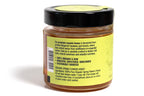 Clear glass jar filled with golden honey, featuring a bright yellow label with clean, modern design. The jar is displayed against a white background, emphasizing the rich amber color of the honey and the vibrant label, ideal for a natural or artisanal product presentation.