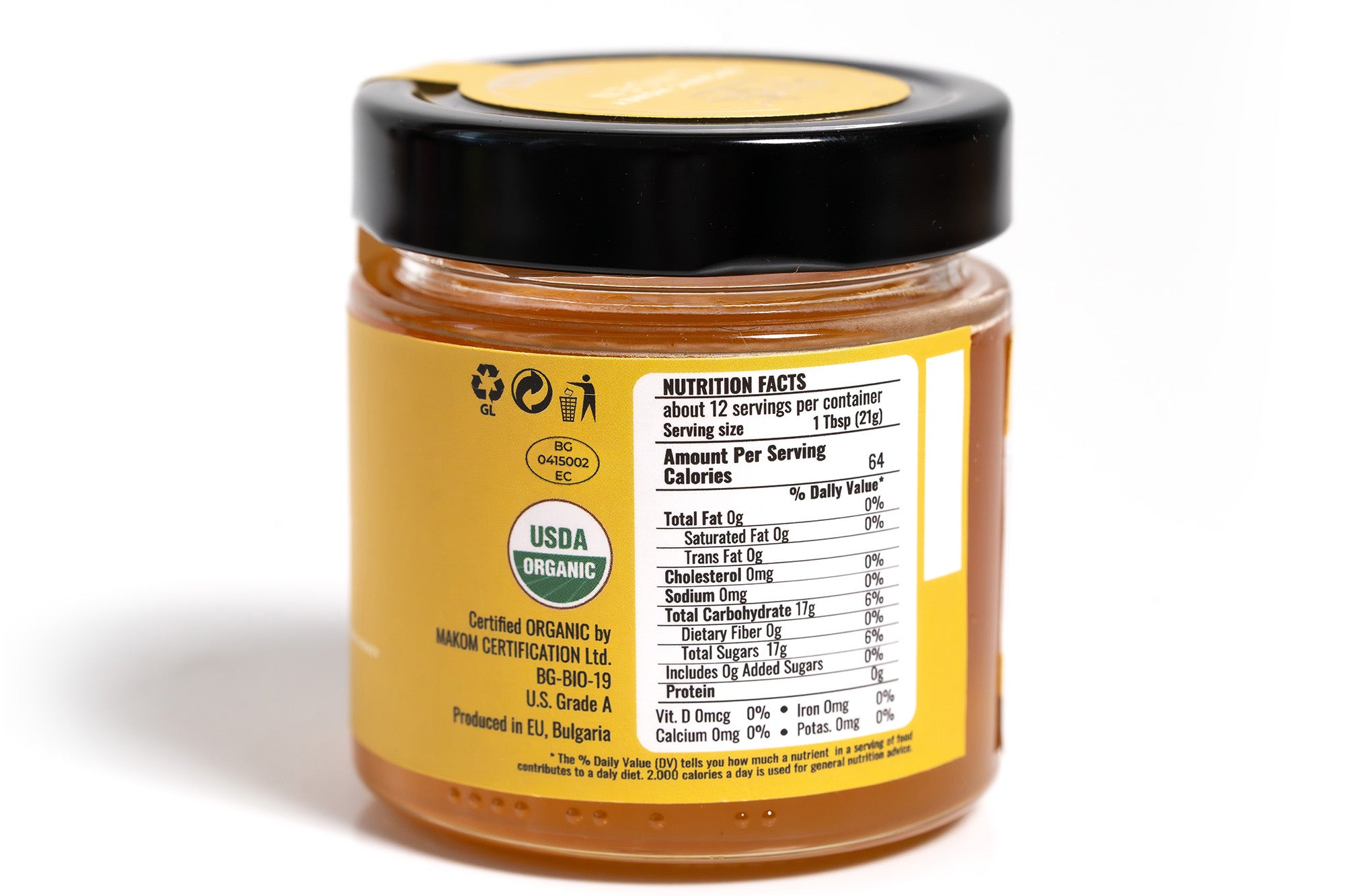 Glass jar of honey with a clearly visible front label displaying product branding and details, filled with golden amber honey. The jar is positioned against a clean white background, highlighting the label design and natural color of the honey.