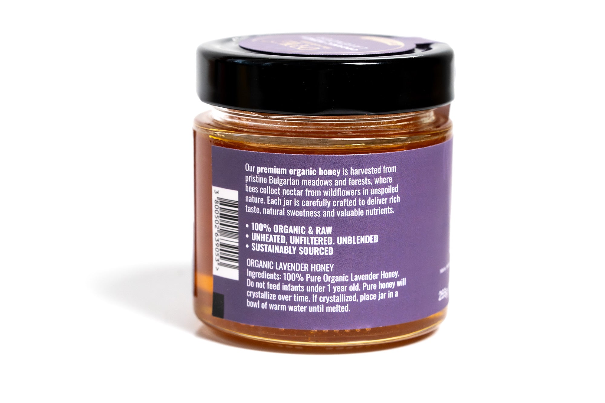 Glass jar of honey with a rich amber hue, featuring a purple label with elegant typography and minimalistic design, set against a clean white background.