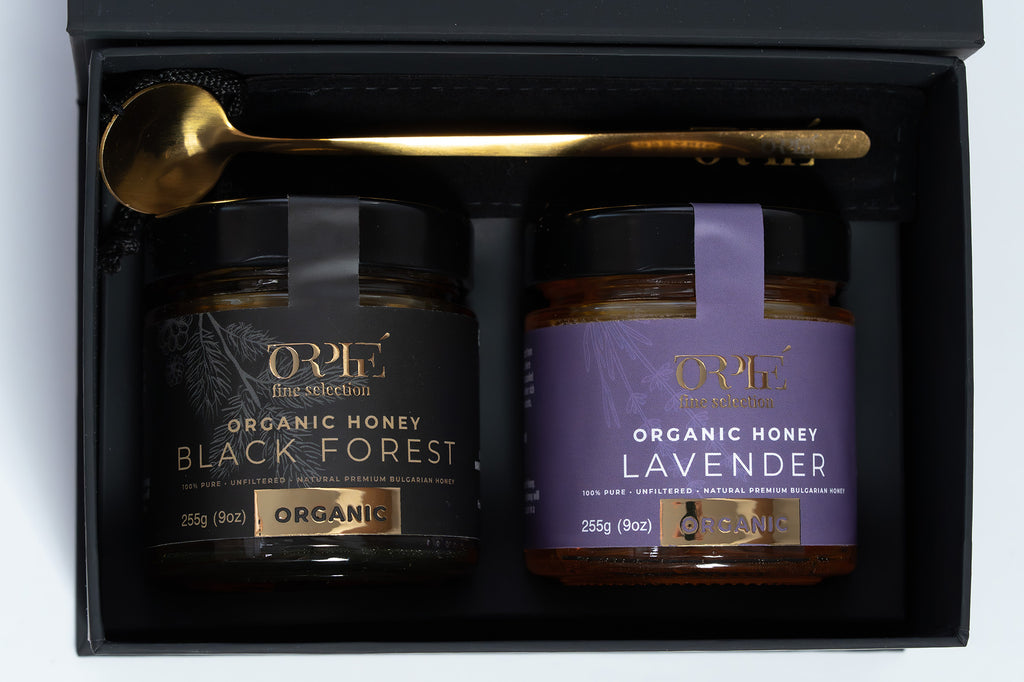 Orphe fine selection gift box with Two jars of organic honey, one labeled 'Black Forest' and the other 'Lavender', in a black gift box with a gold spoon.